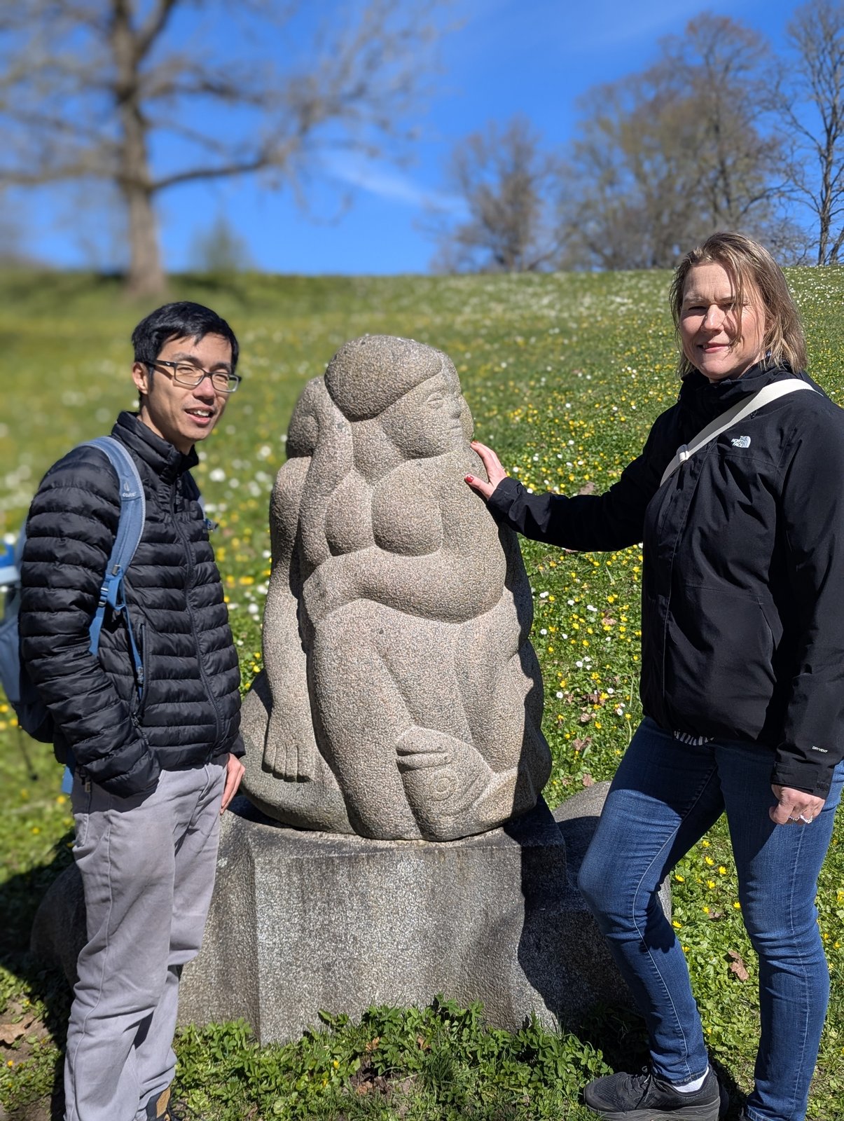 Daiga e um cliente junto à escultura sentada de mãe e filho na Colina das Dainas, Turaida