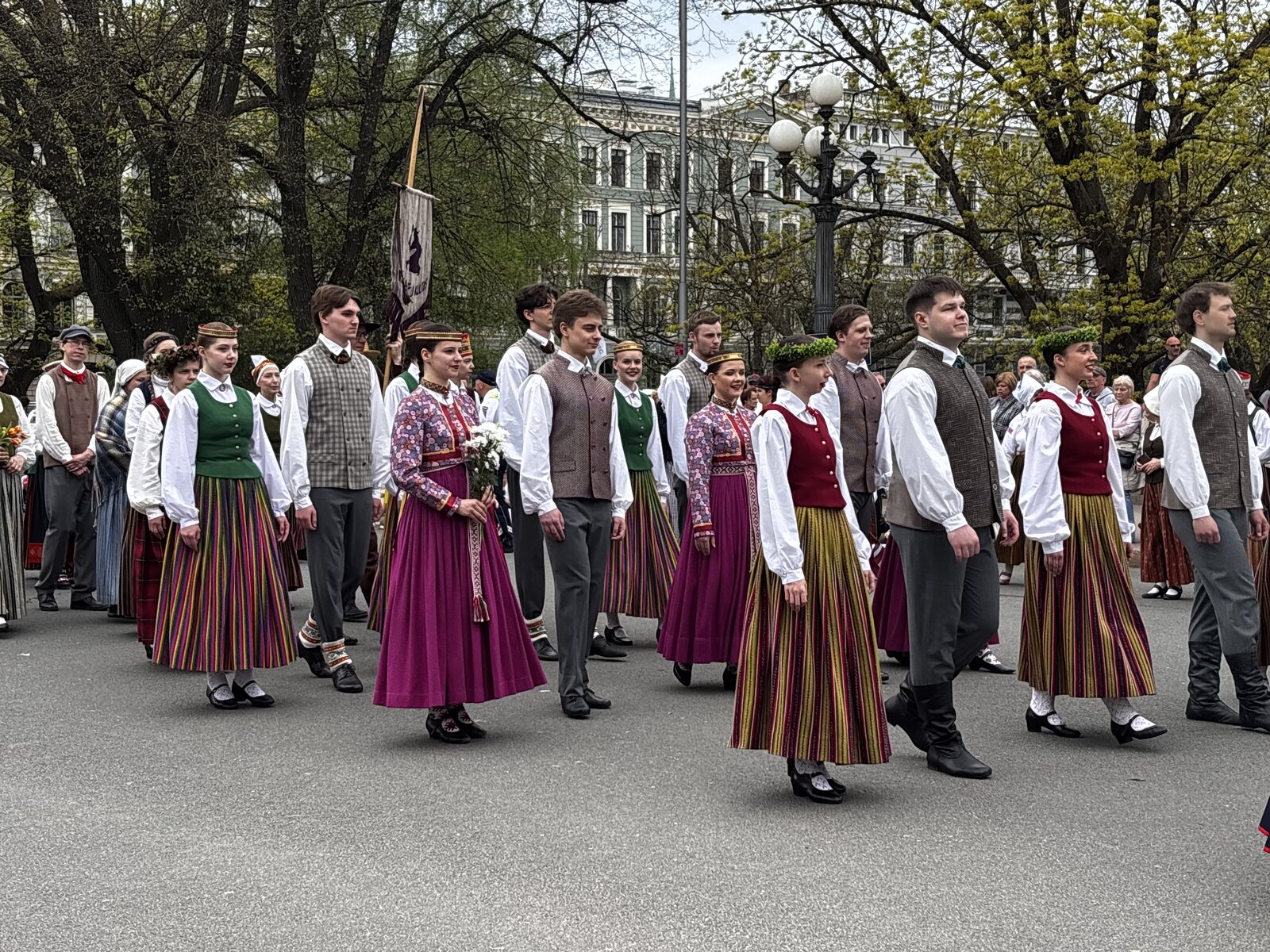 Guarda de honra do Exército letão no Monumento da Liberdade com uma parede de flores depositada junto à base, Riga, no Dia da Restauração da Independência