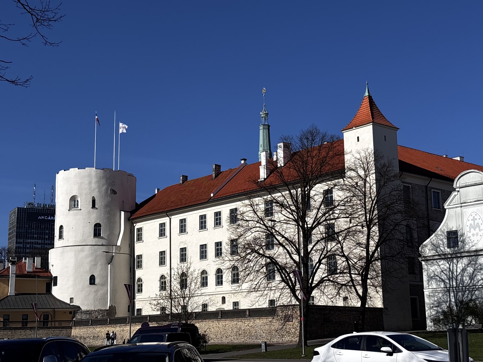 Castelo de Riga (Rīgas pils) com as suas paredes brancas, telhado vermelho e a torre redonda do Espírito Santo em Riga, Letónia.