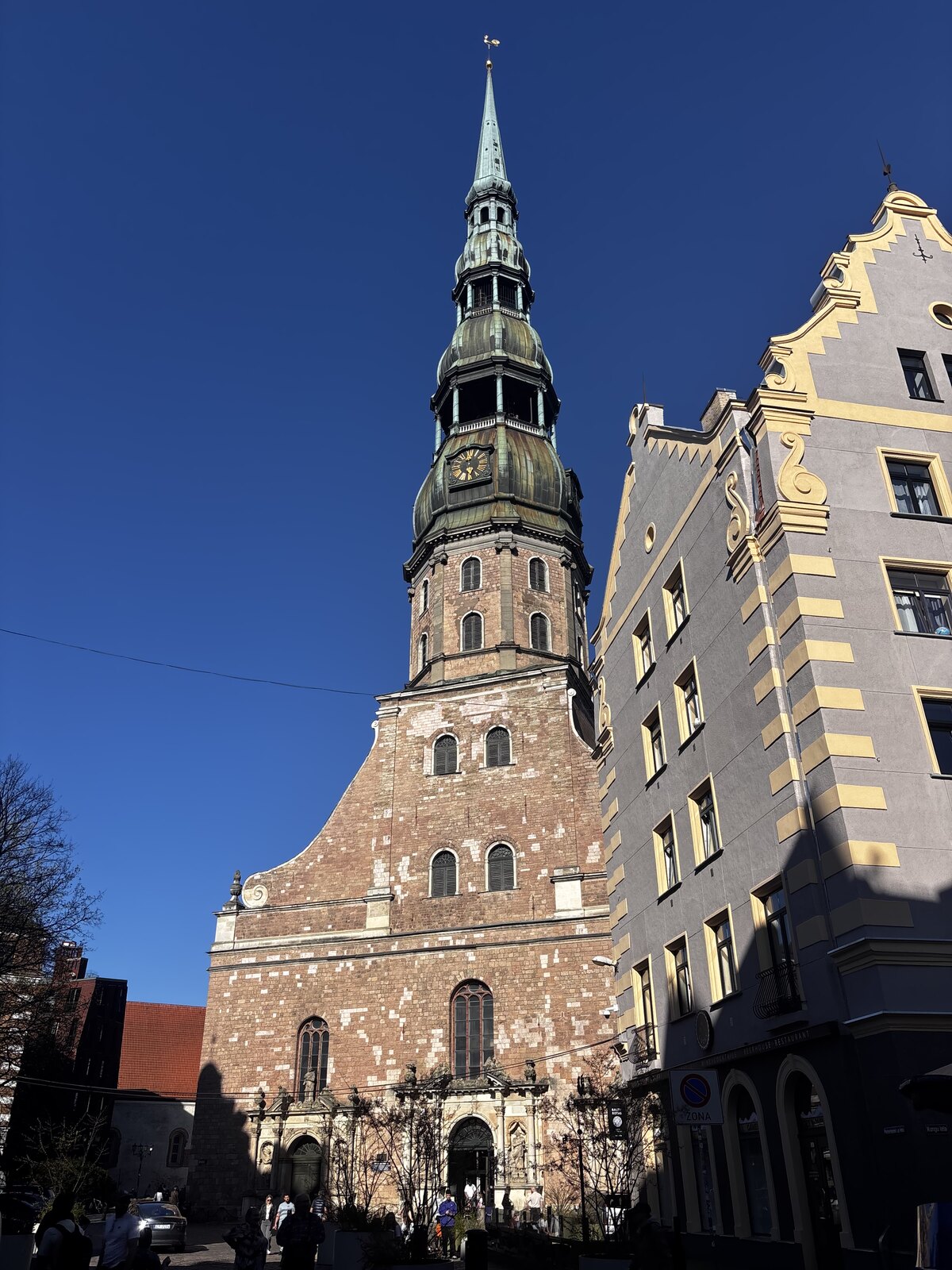Igreja de São Pedro (Sv. Pētera baznīca) com a sua alta torre verde contra um céu azul na Cidade Velha de Riga, Letónia.