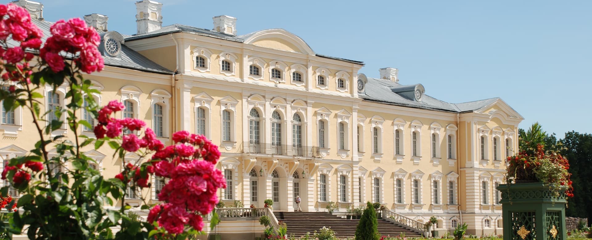 Fachada barroca do Palácio de Rundāle emoldurada pelas rosas no verão