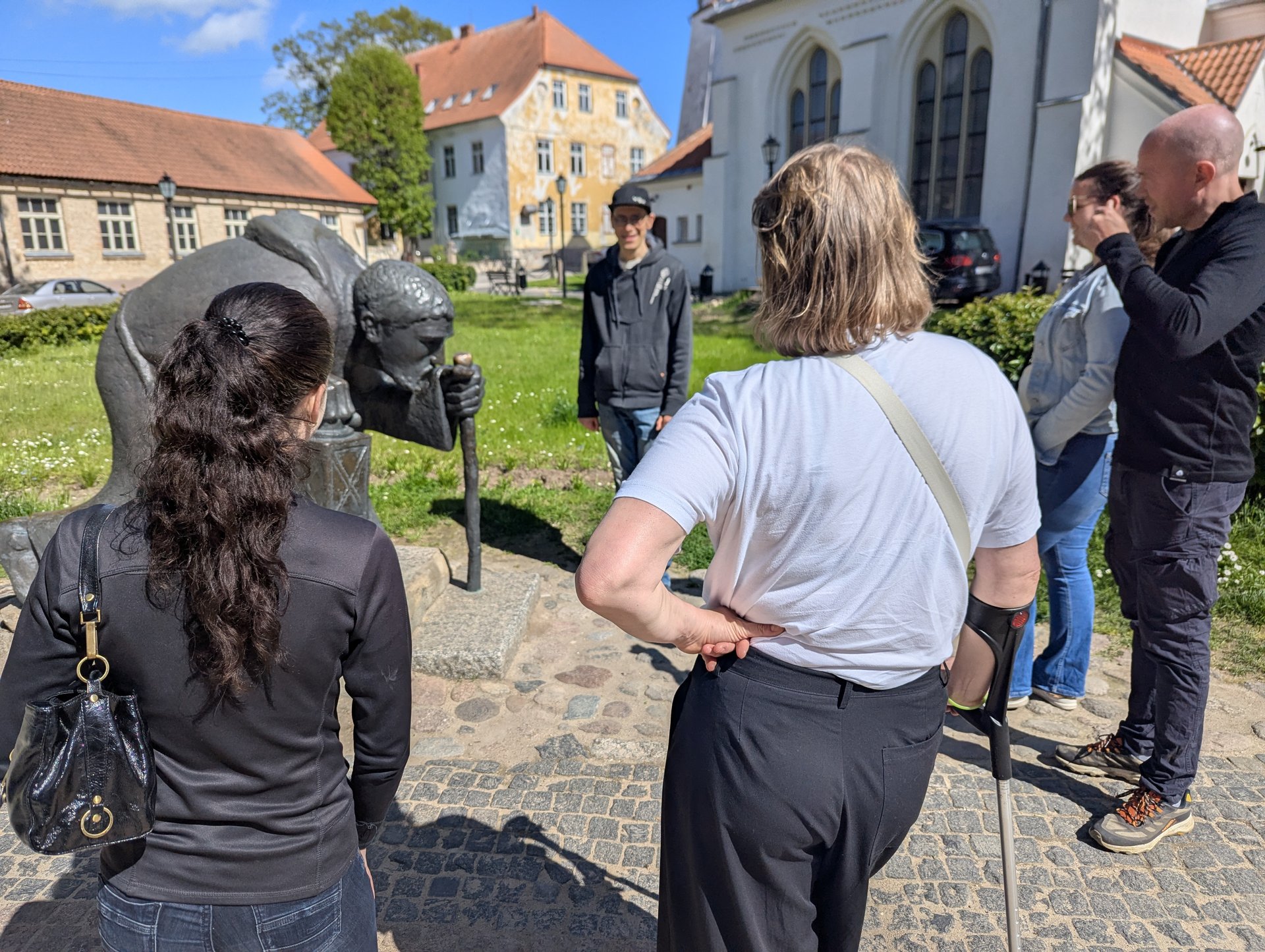 Grupo em torno da escultura de bronze do peregrino no centro histórico de Cēsis