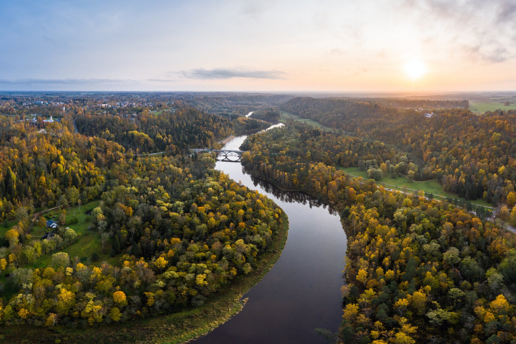 O rio Gauja ao pôr do sol, a atravessar a floresta de outono