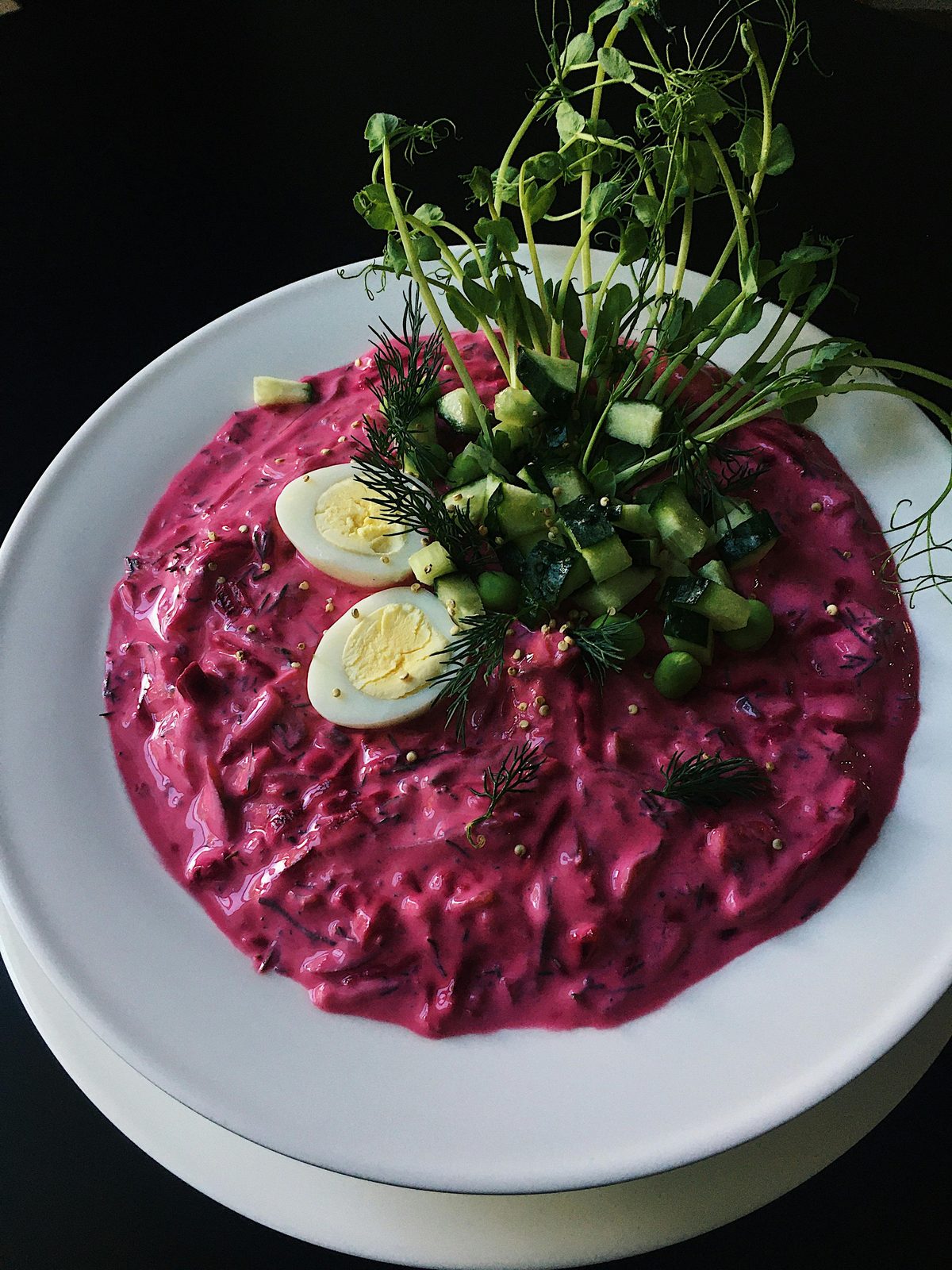 Uma taça de aukstā zupa rosa-vivo, a sopa fria de verão letã de kefir e beterraba, guarnecida com ovo cozido, pepino e endro