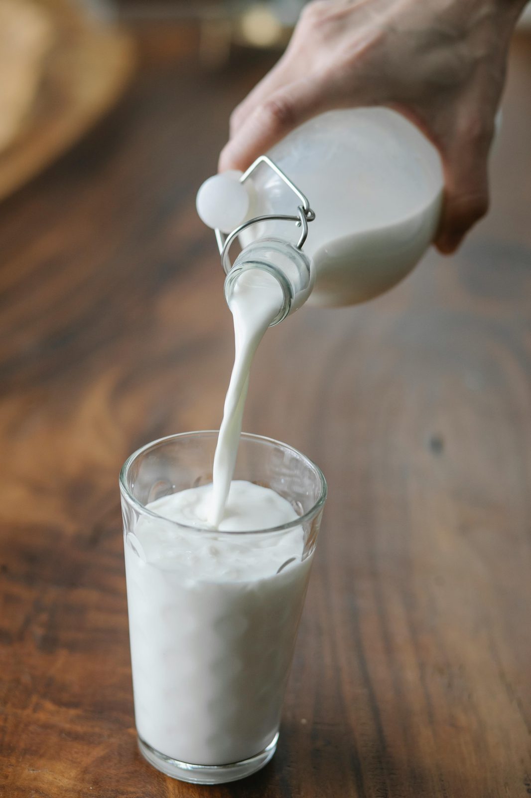 Kefir letão a ser despejado de uma garrafa para um copo sobre uma mesa de madeira