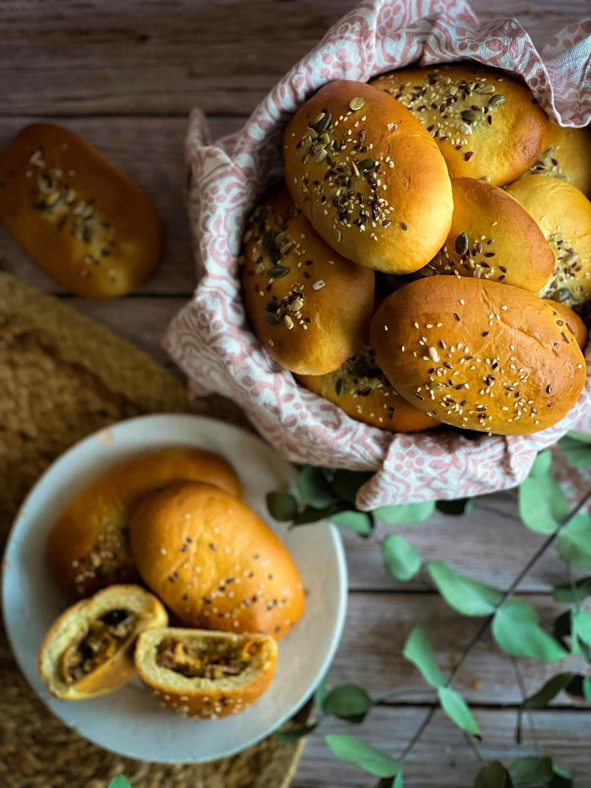 Um cesto de pīrāgi letões dourados polvilhados com sementes, pãezinhos recheados tradicionais